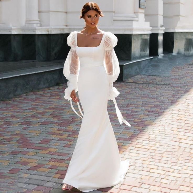 a woman in a white dress standing on a brick walkway