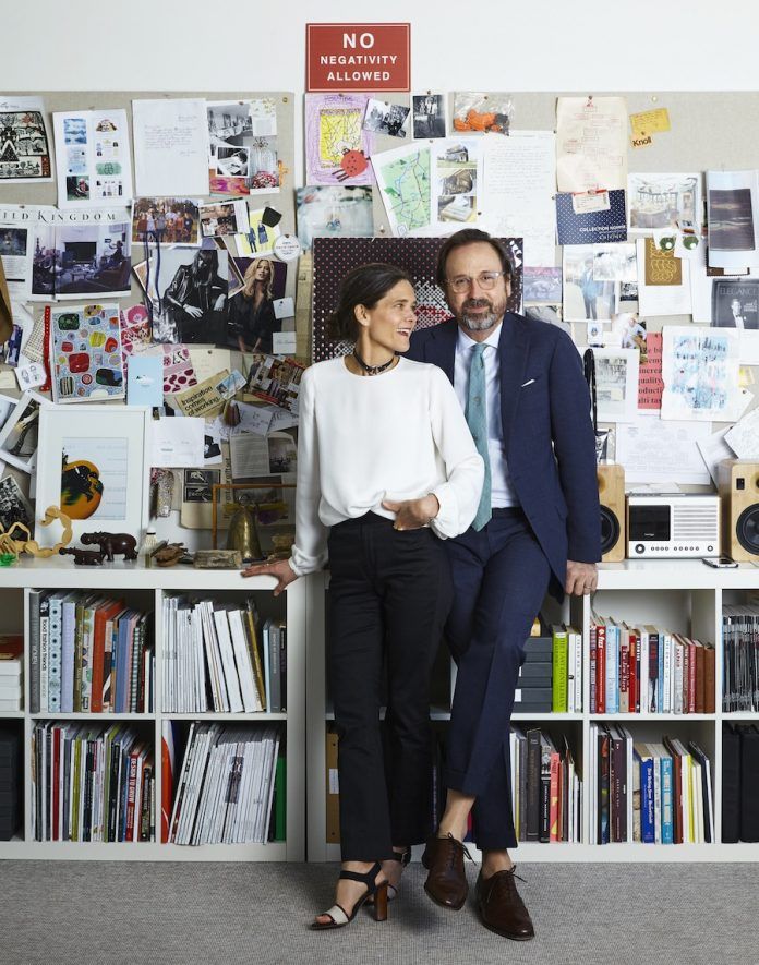 a man and woman standing next to each other in front of a book shelf filled with books