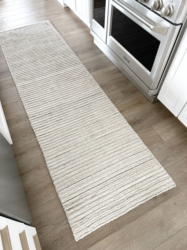 a white rug in the middle of a kitchen floor next to an oven and stove