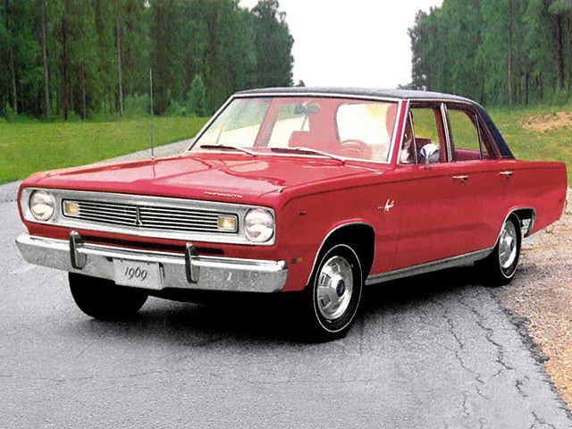 an old red car is parked on the side of the road in front of some trees