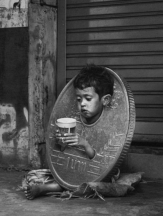 a young boy sitting on the ground holding a beer