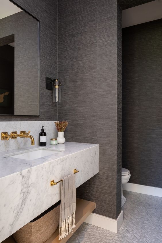 a bathroom with marble counter tops and gold faucets on the sink, along with black walls