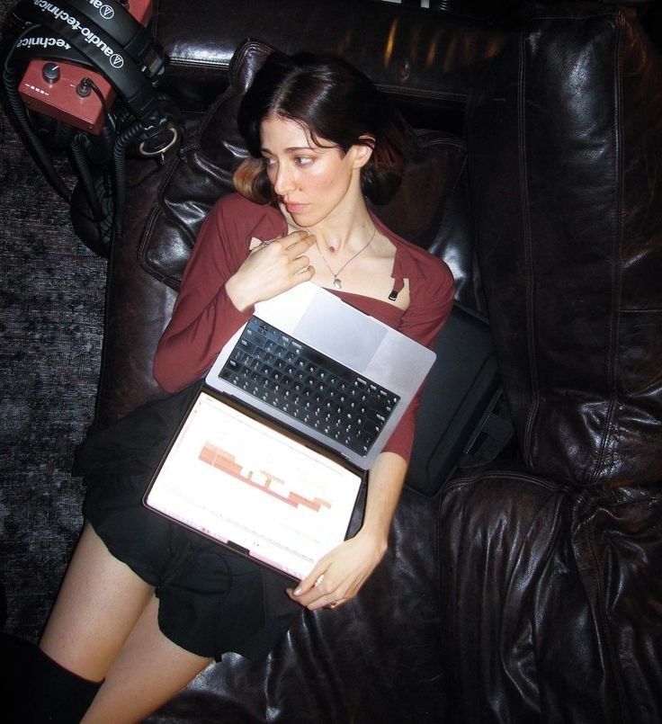 a woman sitting on a couch holding two laptops