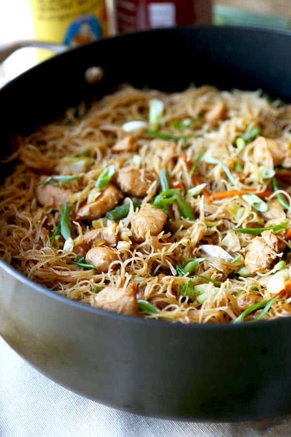 a pan filled with noodles and chicken on top of a table