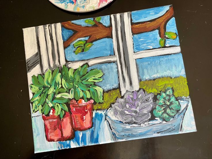 a painting on a table next to a potted plant and a plate with flowers