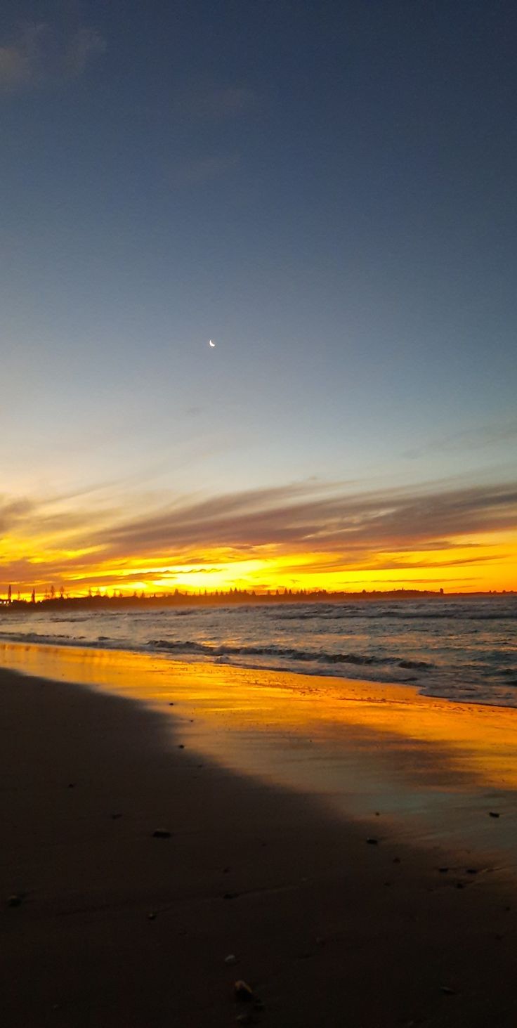 the sun is setting over the ocean and beach