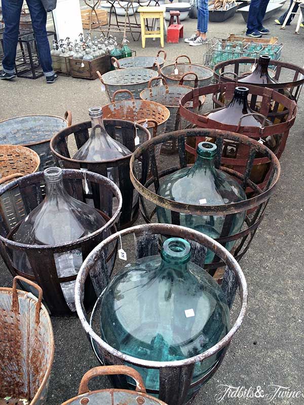 several metal buckets filled with glass bottles on top of cement floor next to tables and chairs