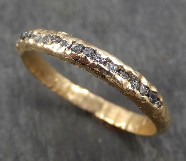 a yellow gold wedding band with diamonds on it's sides, sitting on the ground