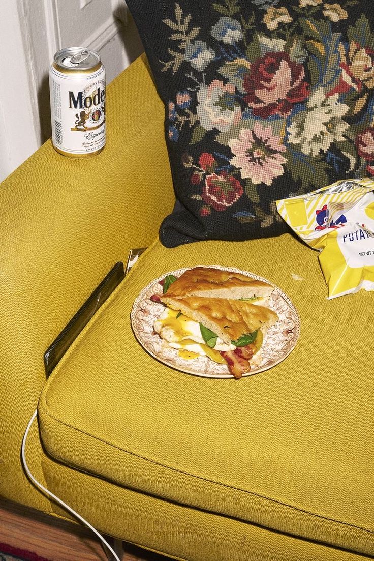 a plate of food sitting on top of a yellow chair next to a can of soda