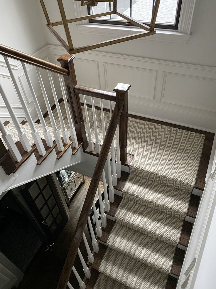 an overhead view of a stair case in a house with white railings and wood handrails