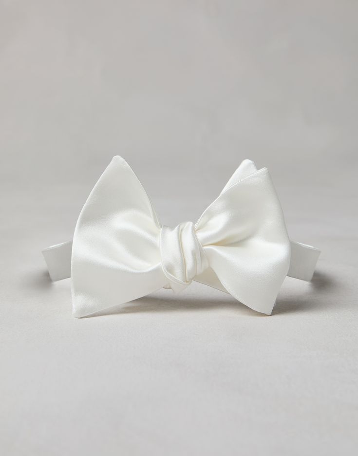 Cotton and silk satin bow tie An essential accessory for evening events, the cotton and silk satin bow tie completes tuxedos with classic flair. This accessory, which must be tied, is adjustable thanks to a convenient hook-and-loop closure behind the neck. Pre-tied Satin Bow For Black Tie Events, Standard Tie Satin Bow, Classic Pre-tied Decorative Bow, Classic Pre-tied Satin Bow Tie, Classic Adjustable Bow With Detachable Feature, Elegant Pre-tied Adjustable Bow Tie, Classic Wedding Ties With Satin Finish, Elegant Adjustable Pre-tied Bow, Classic Silk Ties For Wedding