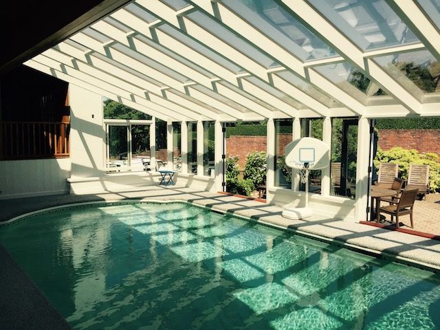 an indoor swimming pool with sun shining through the glass doors and windows on both sides