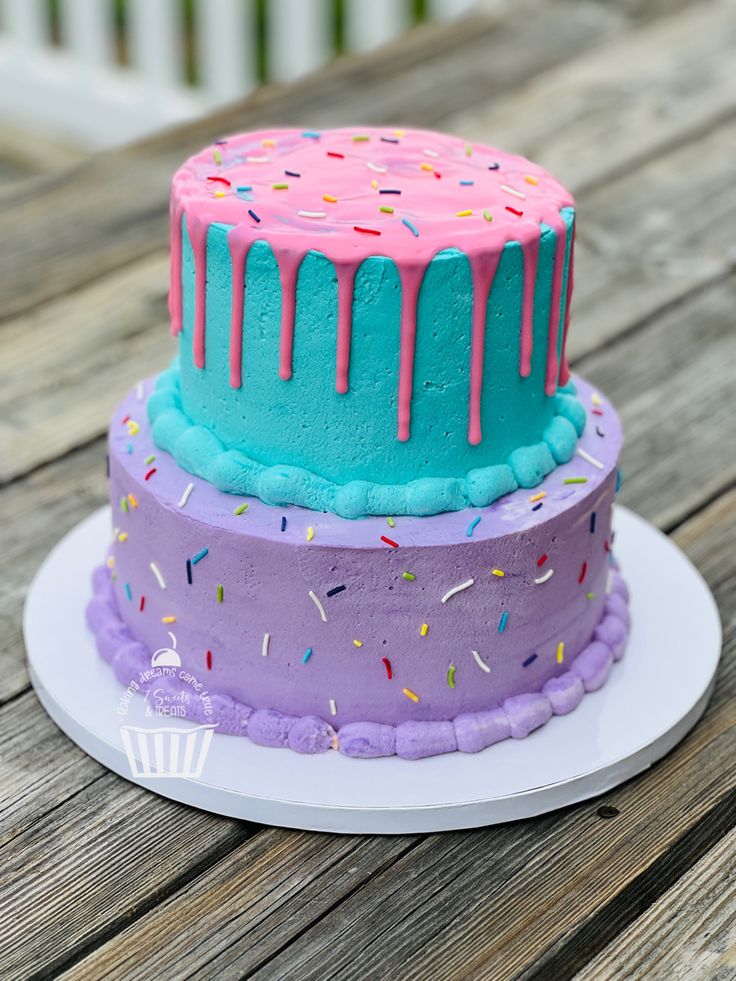 three tiered birthday cake with sprinkles and frosting on a wooden table