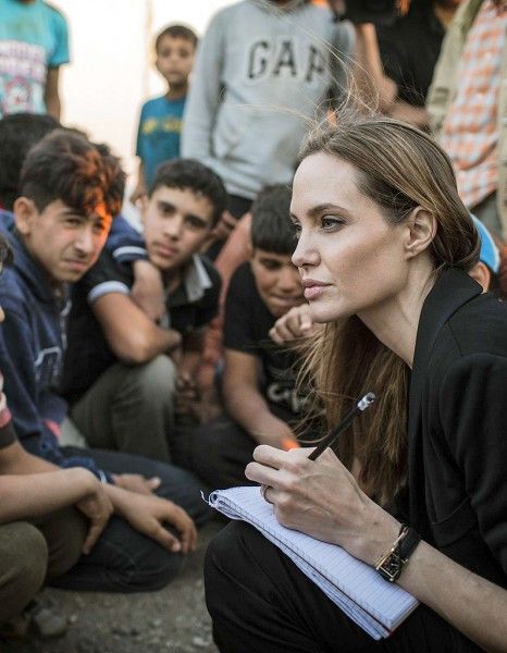 a group of people sitting on the ground with one woman holding a pen and looking at something