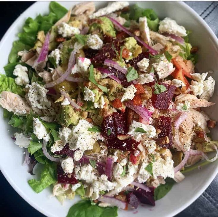 a salad in a white bowl with lettuce and cranberries