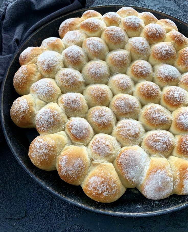 a pan filled with rolls covered in powdered sugar sitting on top of a table