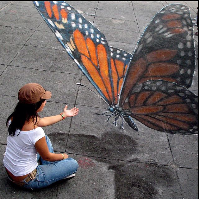 a woman sitting on the ground with a butterfly painted on it's back side