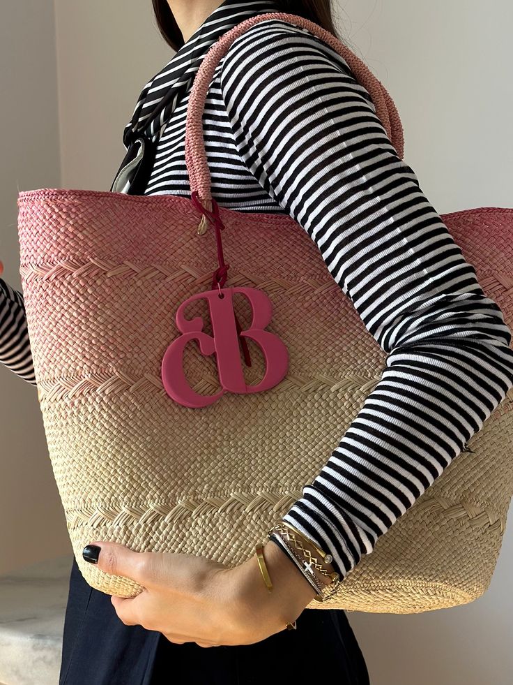 The Isla bag is an elegant basket handwoven out of the finest toquilla straw. It is made by hand in the coasts of Ecuador using a technique that is part of the UNESCO Intangible Cultural Heritage list. The ombre-dyed tote also features the signature Cuckoo B monogram in lacquered ethically-sourced buffalo horn, which is handmade in Vietnam. Pink Beach Bag With Leather Handles, Pink Straw Tote Bag With Braided Handles, Pink Bucket Straw Bag With Braided Handles, Pink Bucket Straw Bag With Handles, Pink Straw Tote Bag With Leather Handles, Casual Pink Handwoven Straw Bag, Pink Handwoven Bucket Straw Bag, Summer Pink Straw Bag With Leather Handles, Pink Straw Bag With Leather Handles For Summer