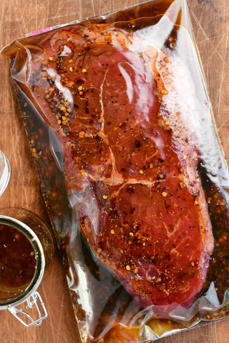 a piece of meat sitting on top of a wooden table next to some sauces