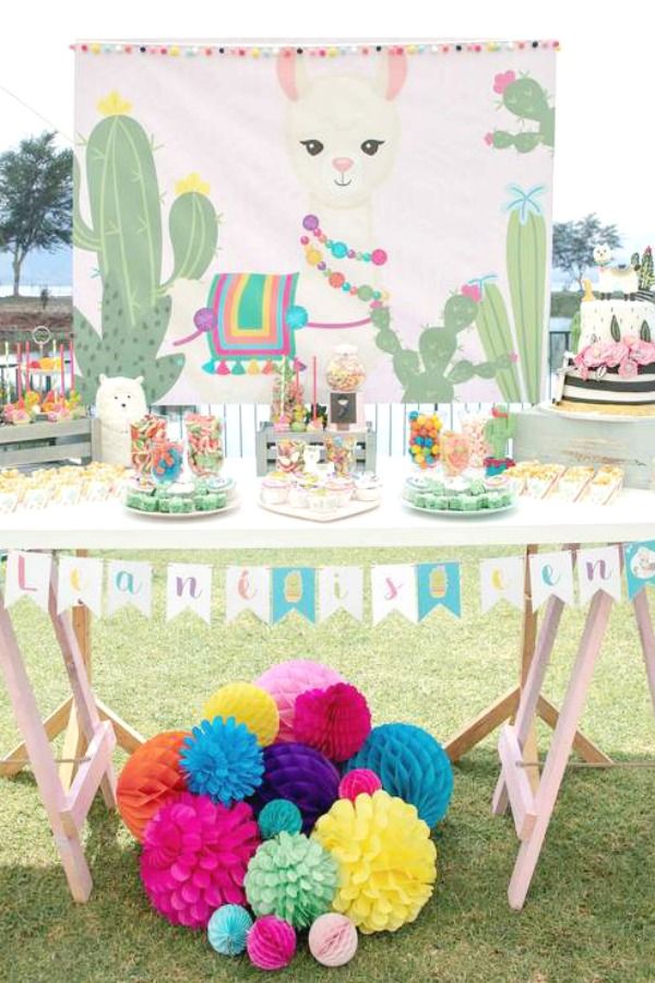 a table topped with lots of colorful paper pom poms next to a cake