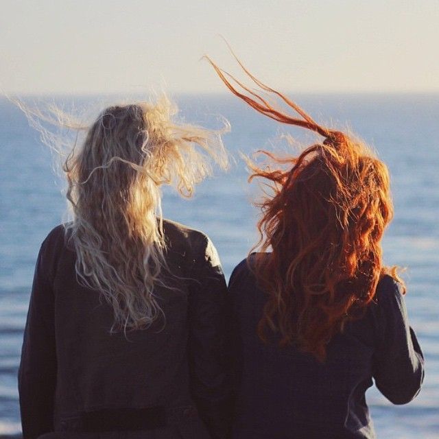 two women with long hair looking out at the ocean