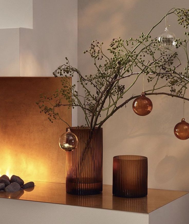 two vases with plants in them on a shelf next to rocks and candlesticks