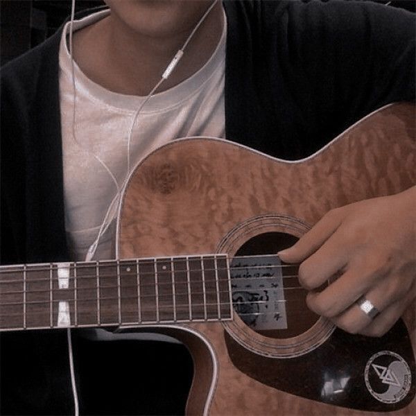 a man is playing an acoustic guitar with headphones in his ears and earbuds