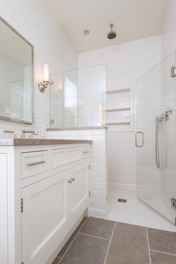 a white bathroom with tile flooring and shower enclosures, including the sink area