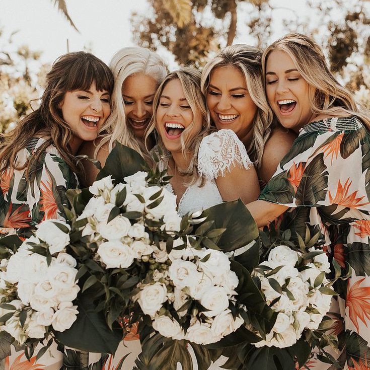 a group of women standing next to each other with flowers in front of their faces