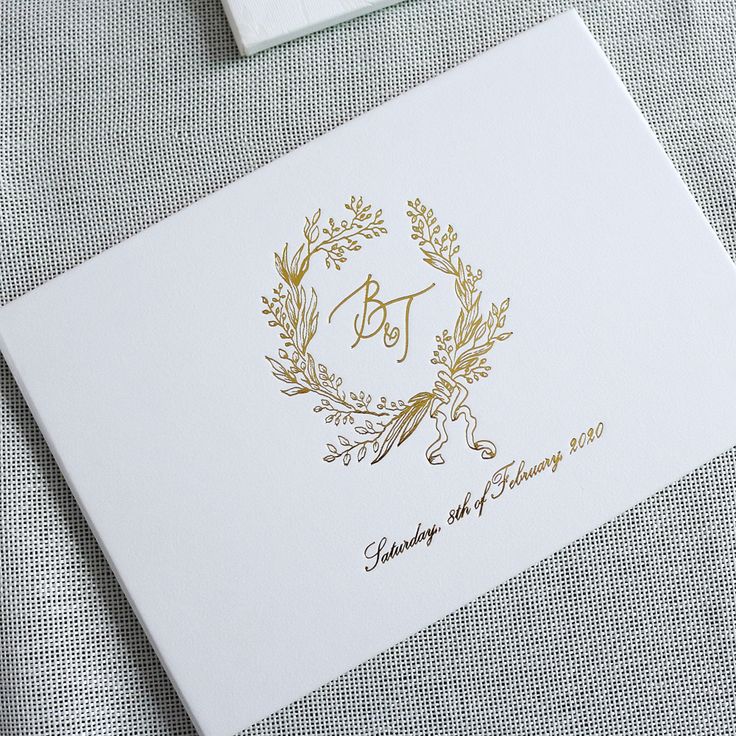 a white envelope with a gold monogrammed wreath on it and the initials bj