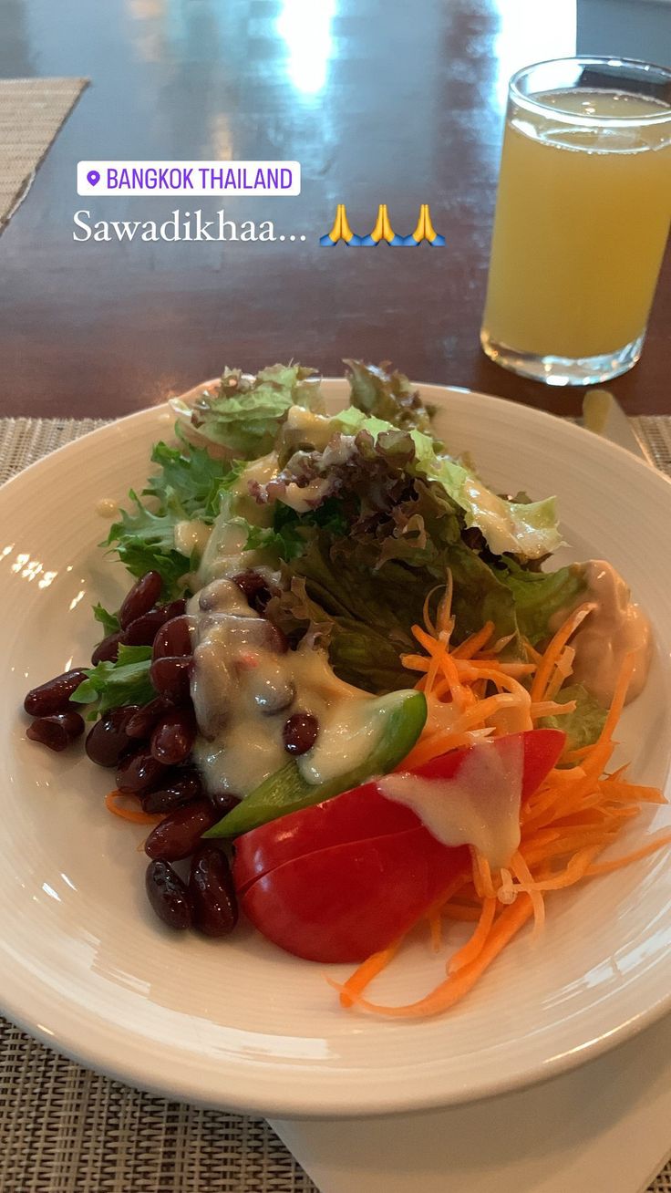 a white plate topped with lots of veggies next to a glass of orange juice