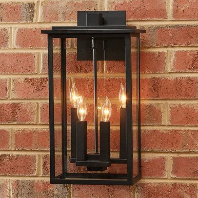 an outdoor wall light with three lights on it's side against a brick wall