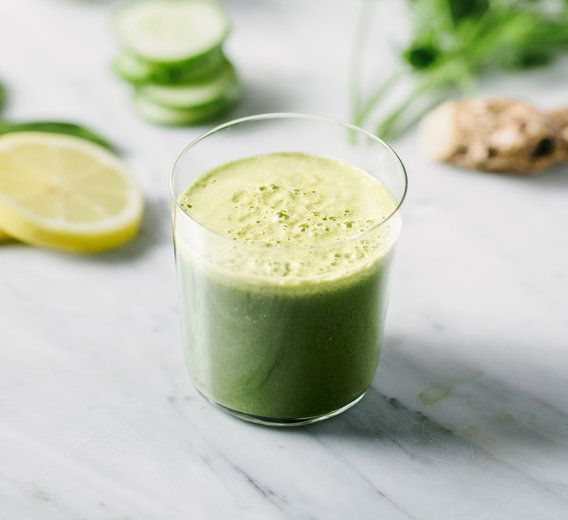 a green smoothie with cucumbers, lemons and mint on the side