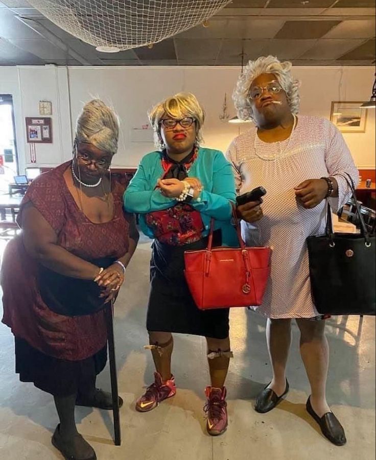 three women standing next to each other holding purses and looking at their cell phones