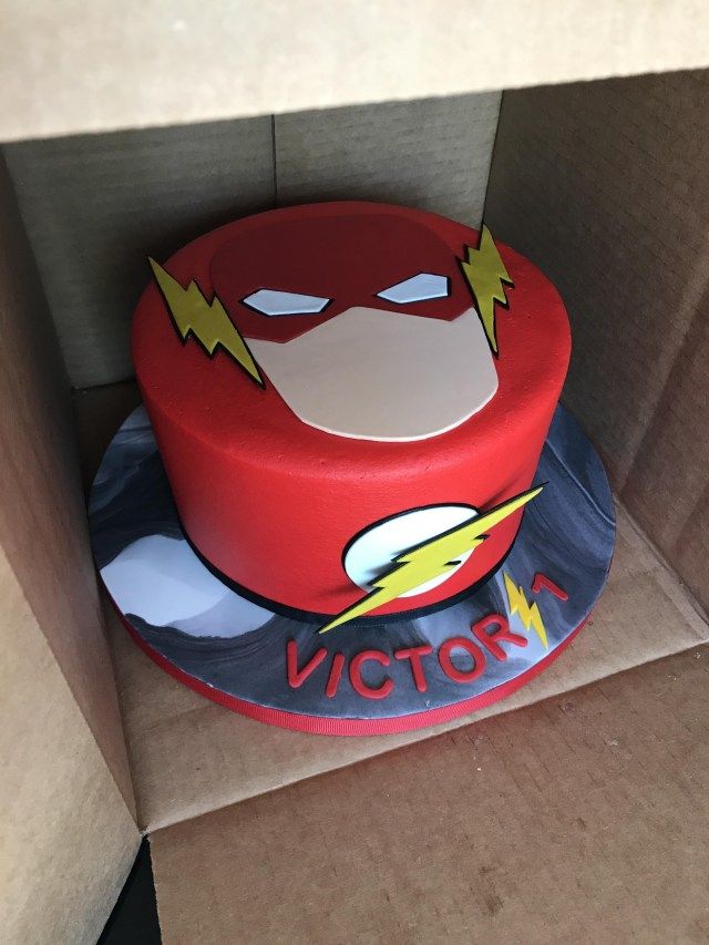 a cake in the shape of a flash man sitting on top of a cardboard box