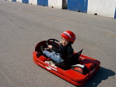 a young boy sitting in a red pedal car