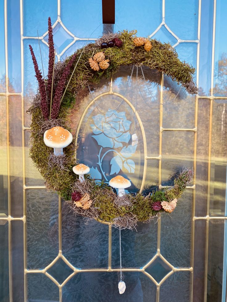 a wreath with mushrooms and moss hanging on the front door to decorate it's entrance