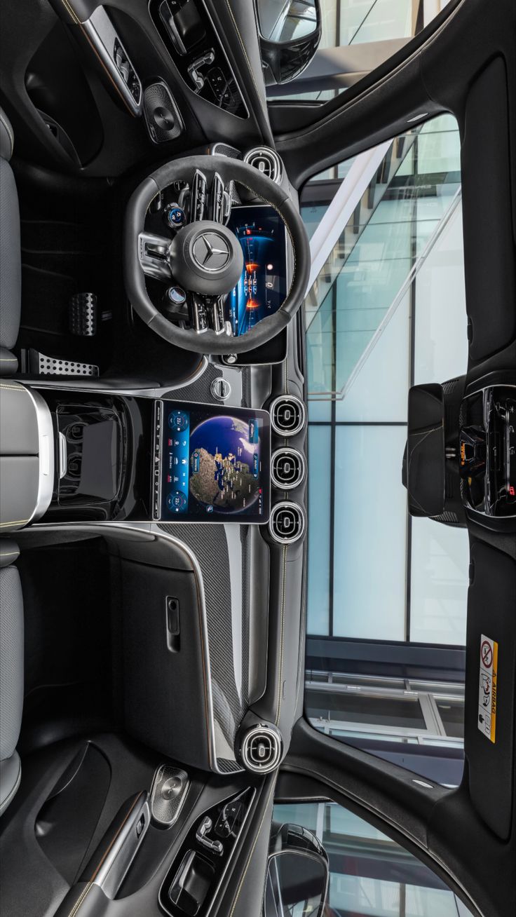 the inside of a car with its dashboard and steering wheel controls on display in front of a large window