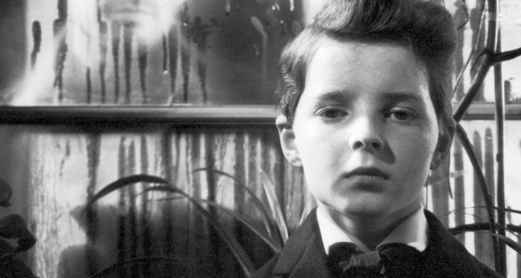 a young boy wearing a suit and bow tie