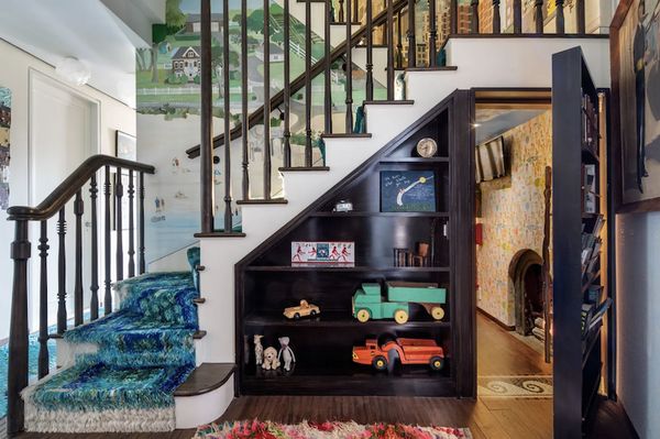 the stairs in this home are decorated with colorful artwork and toys, while carpeted flooring is also visible