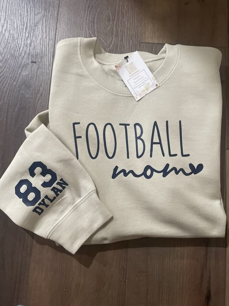 This crew neck sweatshirt makes the perfect gift for football moms. Choose  your size and shirt color from the drop menu below. Make sure to fill out the personalization section with your child's jersey number and name and your choice of font color. This will be added to the sleeve of the shirt. Font colors are navy, black, white, red, gold, bright yellow, forest green, or orange. Email us for a specific color shade.   Adult Unisex  50/50 Fleece Crew Football Mom Sweater, Football Sweatshirts Vinyl, Diy Football Mom Shirts, Football Mom Shirts Ideas Design, Football Mom Shirts Ideas Sons, Sports Mom Shirts Ideas, Football Mom Sweatshirt Ideas, Football Mom Must Haves, Football Shirts Ideas