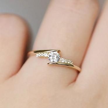 a woman's hand with a gold and diamond ring on top of her finger