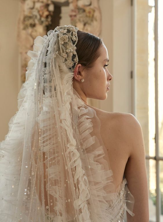 a woman in a wedding dress with a veil on her head looking off into the distance