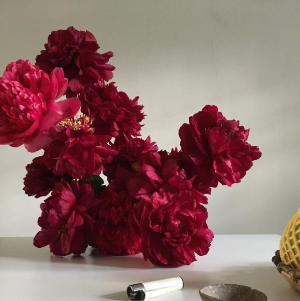 a vase filled with red flowers next to a banana and other items on a table