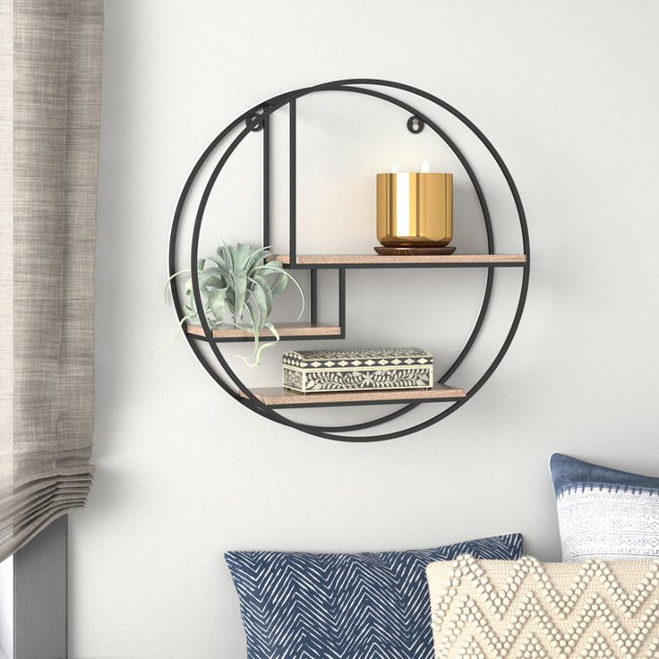 a round metal shelf with candles and books on it next to a window sill