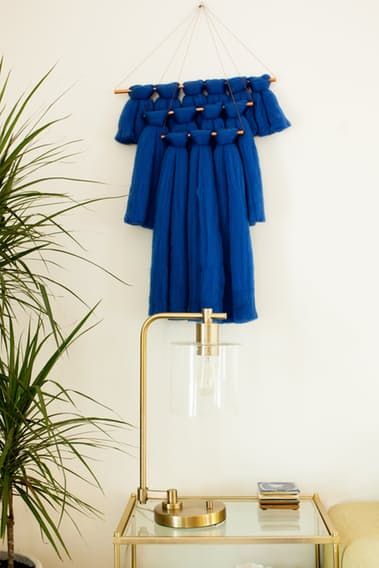 a blue dress hanging on a wall next to a potted plant and a chair