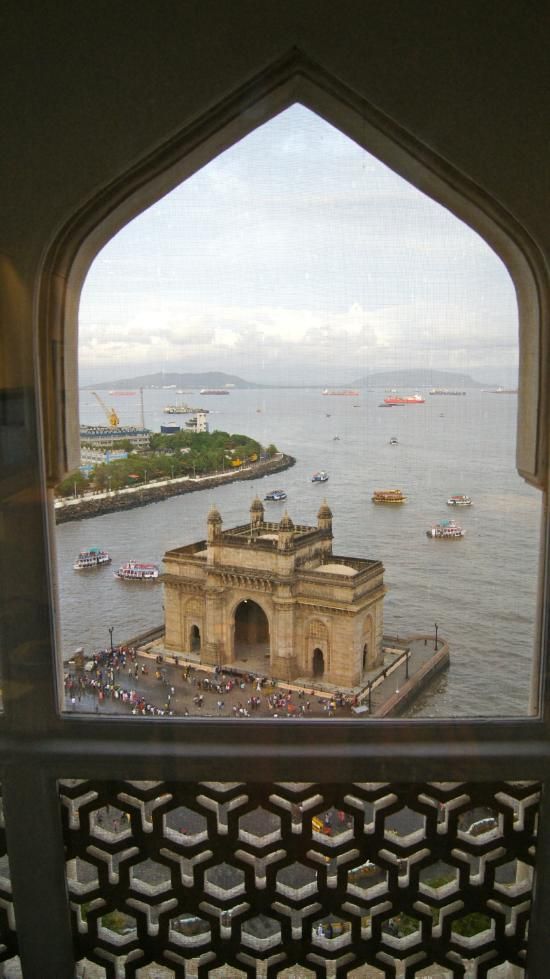 the view from an arched window looking out at boats on the water and buildings in the distance