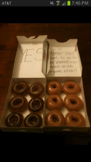 an open box of doughnuts sitting on top of a wooden table next to a note