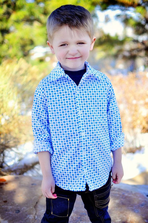 a young boy standing on top of a rock in the snow wearing jeans and a blue shirt