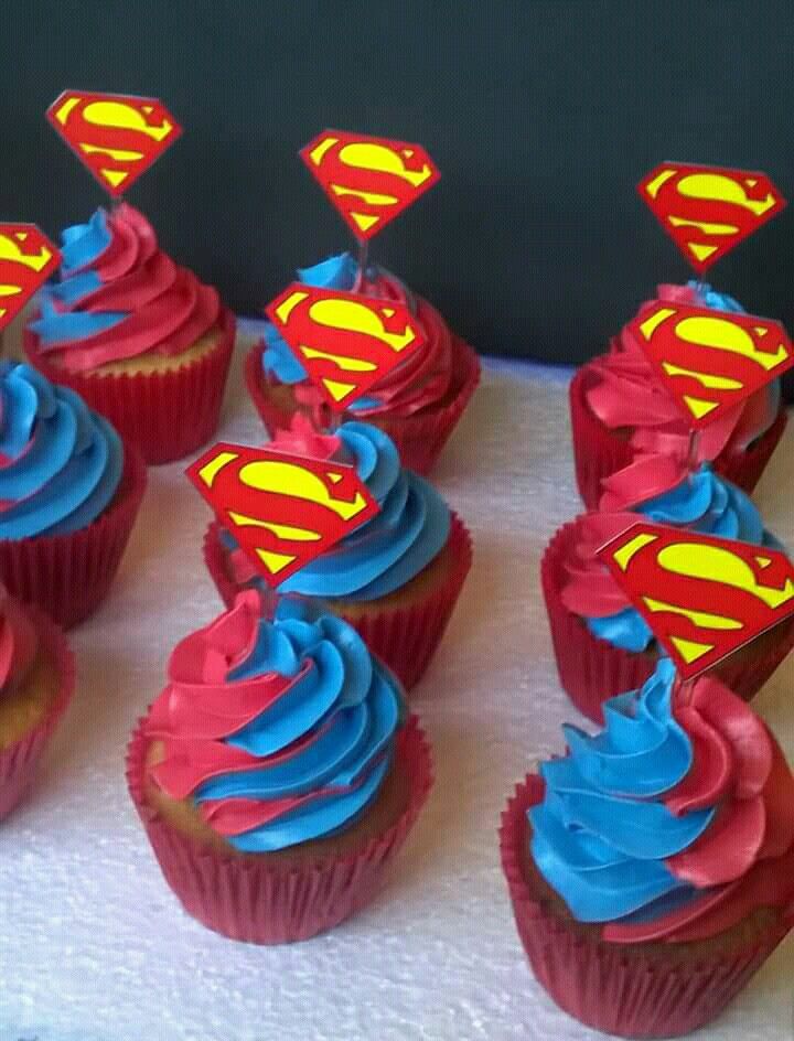 cupcakes with blue frosting and red icing are arranged on a table